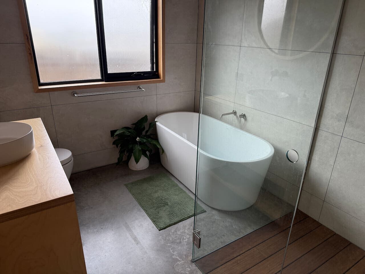 Une salle de bain moderne avec une douche à parois de verre, une baignoire sur pieds et un meuble-lavabo en bois.