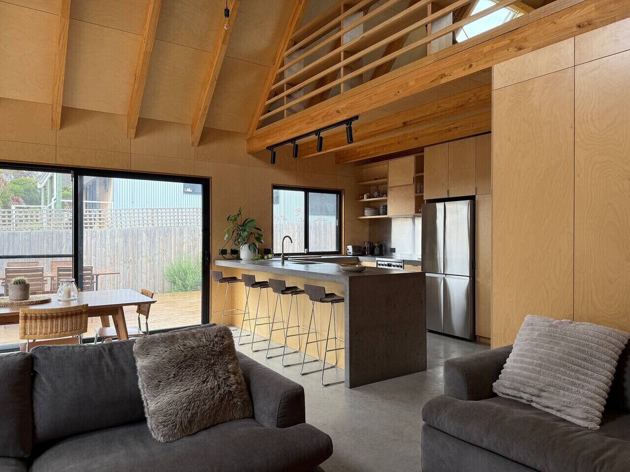 Et moderne køkken med en central ø, barstole og et spiseområde med et bord og stole.