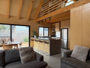 Een moderne keuken met een centraal eiland, barkrukken en een eethoek met een tafel en stoelen.
