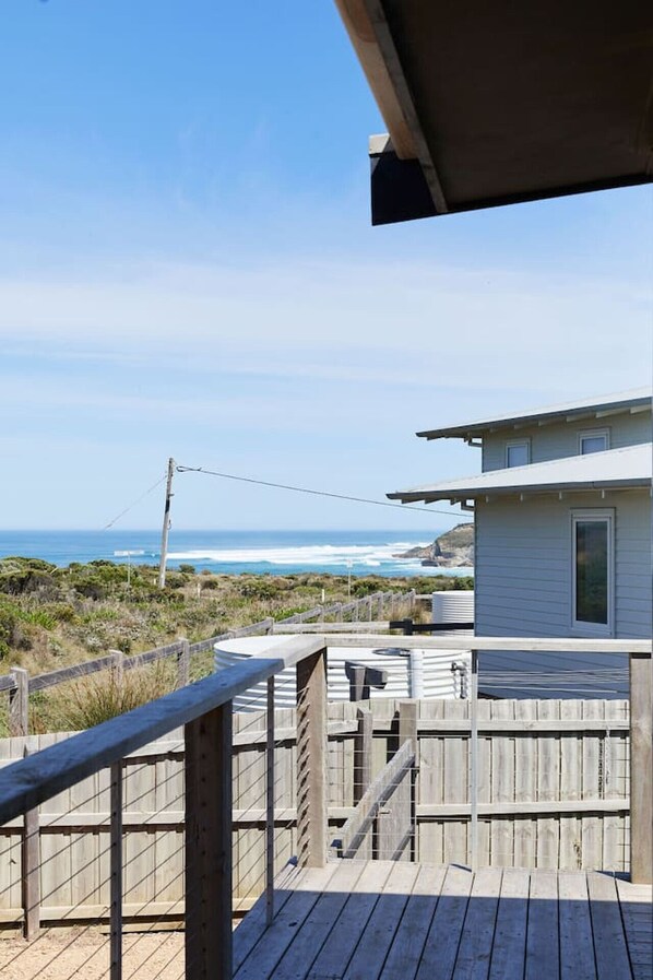 A wooden deck with a view of the ocean and a small building.
