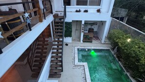 A modern two-story house with a swimming pool, a wooden staircase, and a balcony.