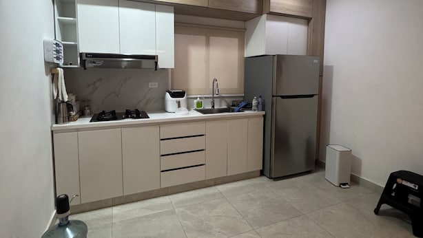 A modern kitchen with a built-in oven, a refrigerator, and a sink.