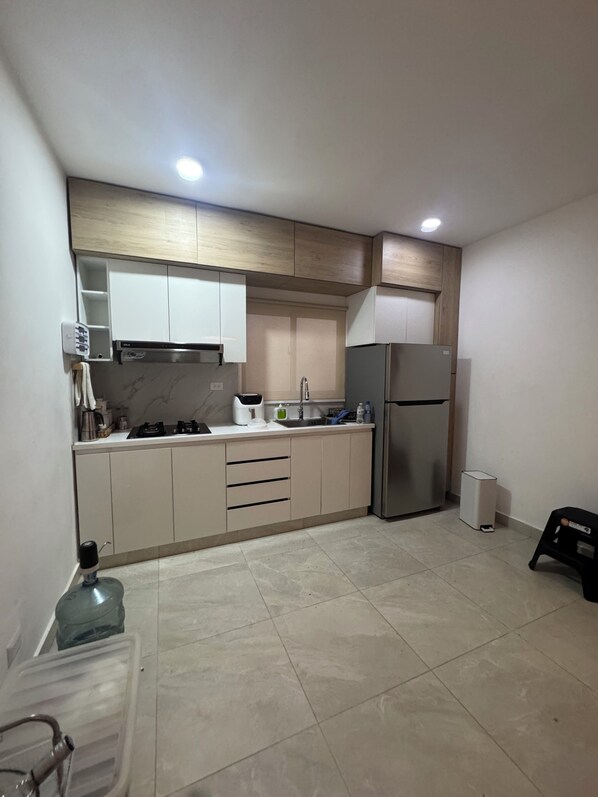 A modern kitchen with a built-in oven, a refrigerator, and a sink.