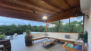 A spacious outdoor seating area with a wooden ceiling, a sofa, and a coffee table.