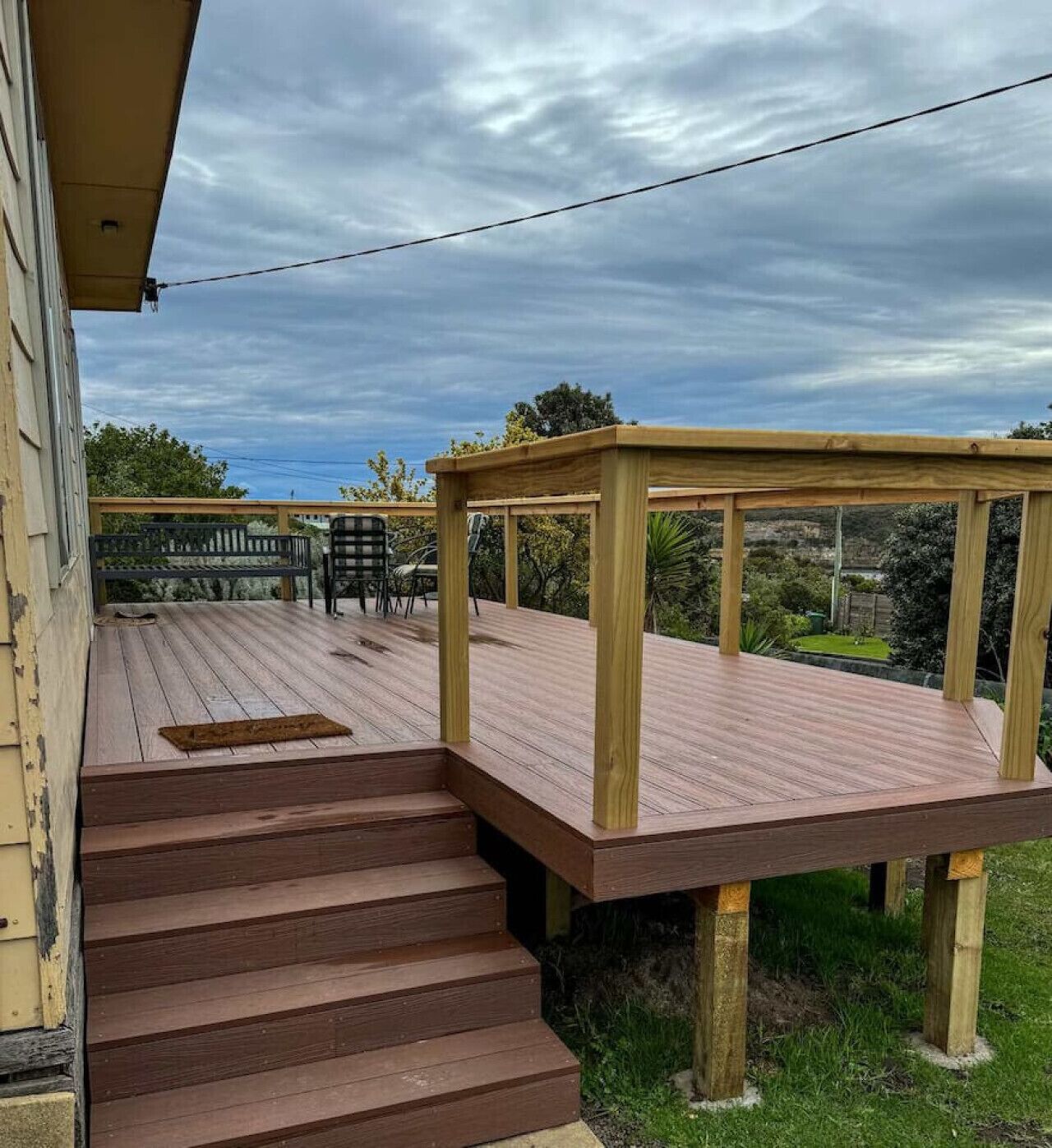 Une terrasse en bois avec un banc et une table, qui mène à un escalier.