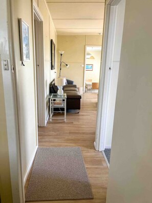 A hallway leading to a living area with a sofa, a lamp, and a small table. - Hennessy Beach House (Port Campbell)