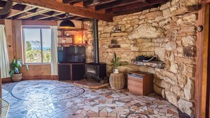 Habitació amb parets de pedra, una llar de foc, televisió i terra de rajola.