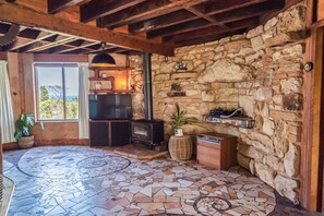 A stone-walled room with a fireplace, a television, and a tiled floor. - Pixies at Ecobay Port Campbell (Port Campbell)