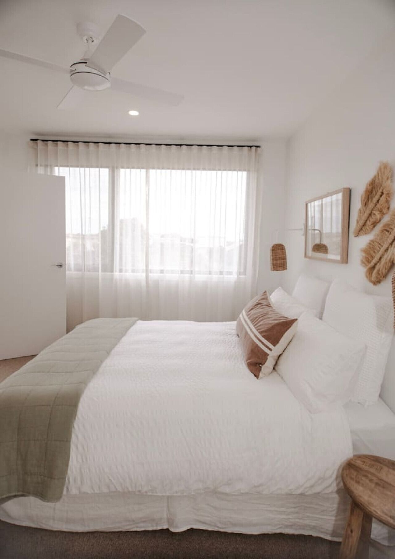 A bedroom with a bed, a ceiling fan, a window with curtains, and wall-mounted decor.