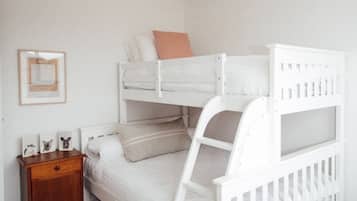 Un lit superposé avec une table de chevet en bois à côté.