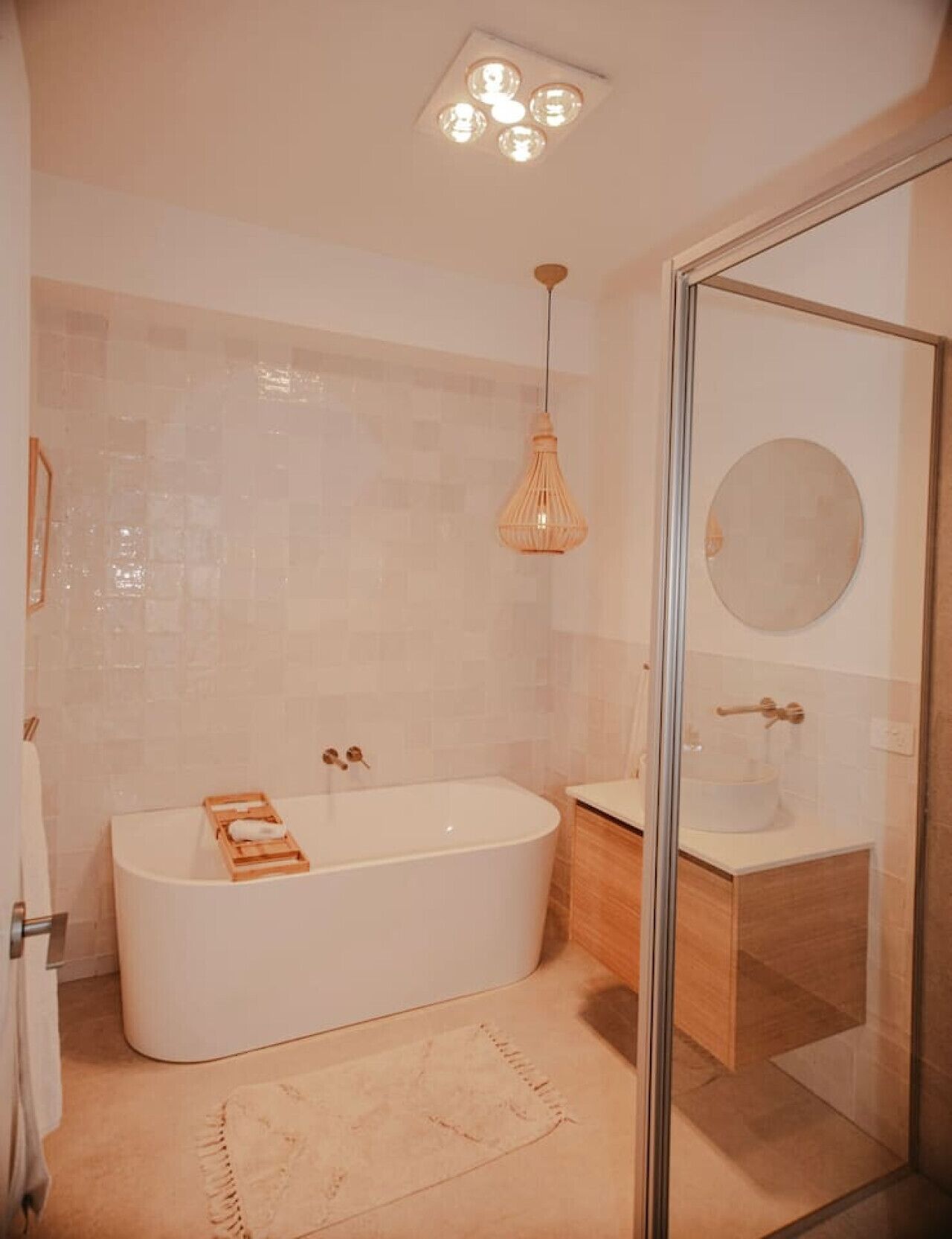A modern bathroom with a freestanding bathtub, a glass-enclosed shower, and a round mirror on the wall.
