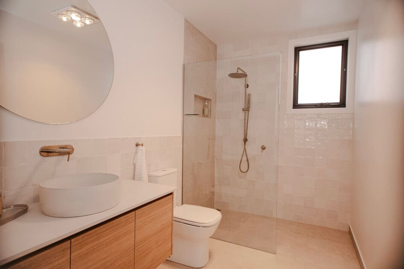Une salle de bain moderne avec un lavabo rond, des toilettes et une douche à l’italienne.