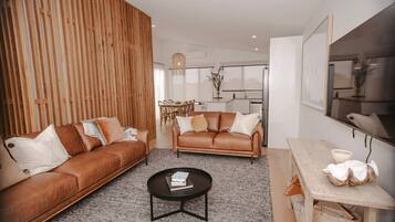 A modern living room with two leather sofas, a coffee table, and a dining area with a wooden table and chairs.