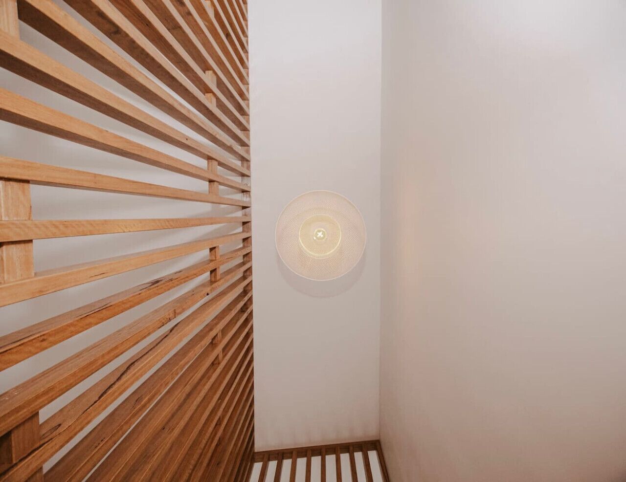 Une pièce avec un mur en bois à lattes et un luminaire circulaire au plafond.