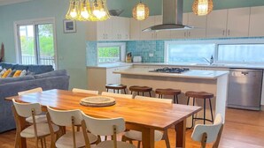 Eine moderne Küche mit einer zentralen Kochinsel, einem Holztisch und Barhocker.