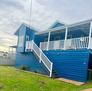 A two-story house with a blue exterior, a white staircase, and a covered porch. - Seabatical Port Campbell (Port Campbell)