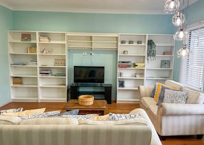 A living room with a television, bookshelves, a sofa, and a coffee table. - Seabatical Port Campbell (Port Campbell)