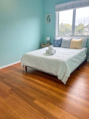 A bedroom with a bed, a nightstand, a lamp, and a window. - Seabatical Port Campbell (Port Campbell)