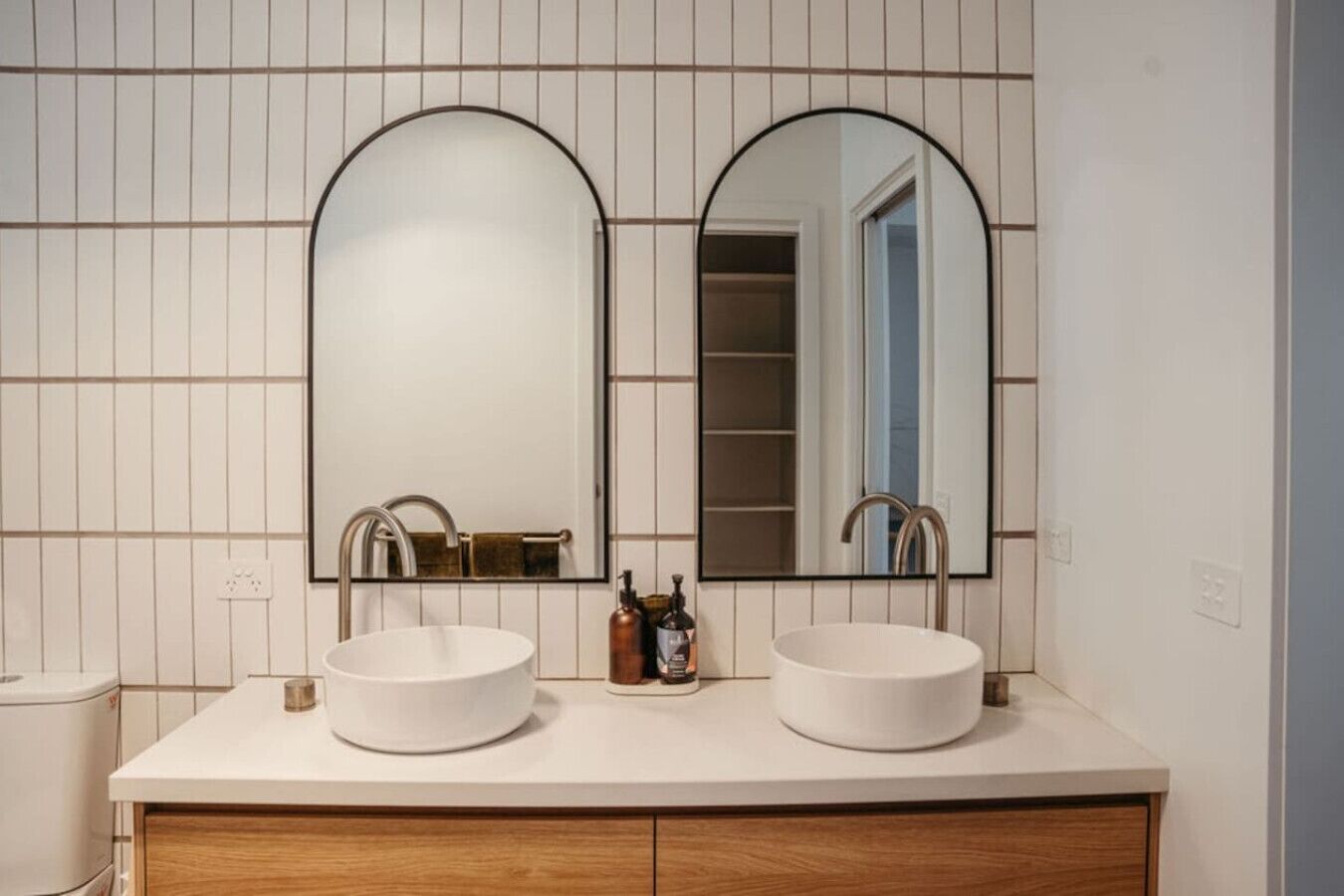 A bathroom with two sinks, a mirror, and a wooden cabinet.