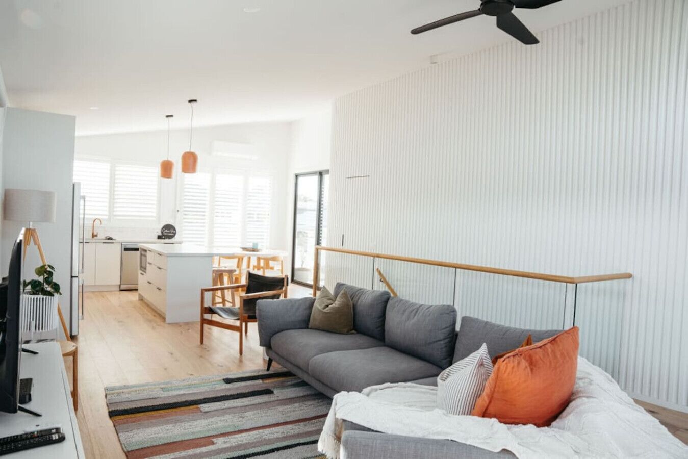 A modern living room with a sofa, a TV, and a dining area with chairs and a table.