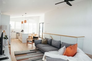 Una sala de estar moderna con un sofá, un televisor y un comedor con sillas y una mesa.