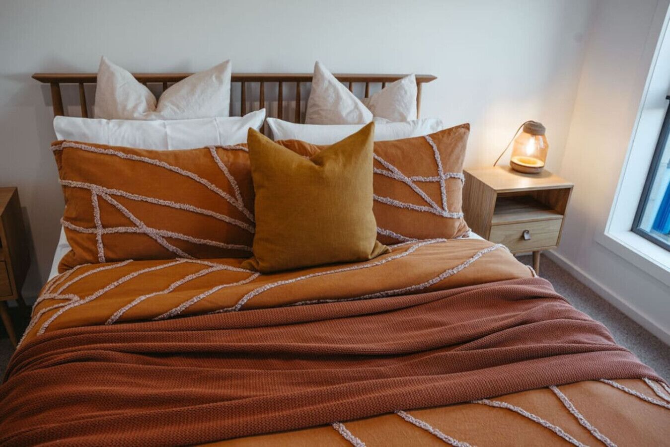 Una cama con cabecera de madera, varias almohadas y una manta marrón.