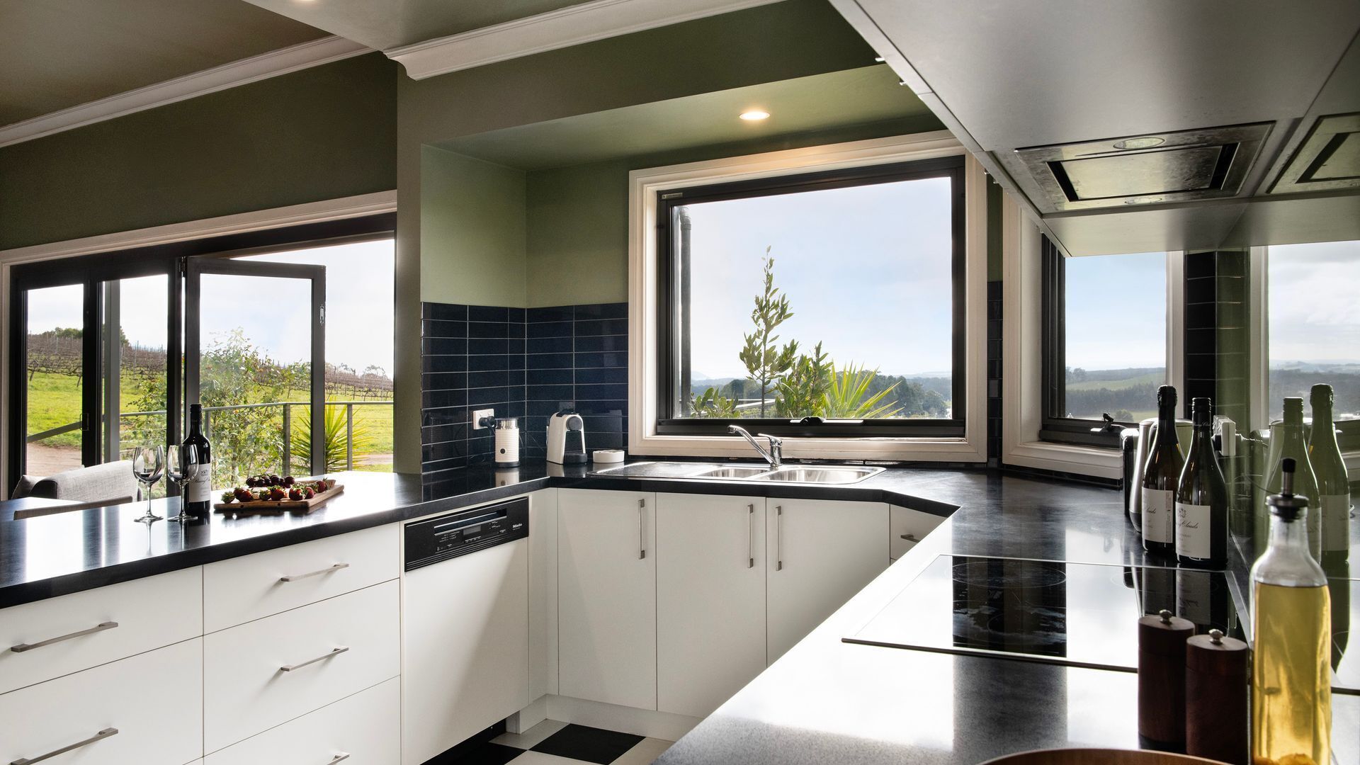 A modern kitchen with a large island, white cabinetry, and a view of the countryside.