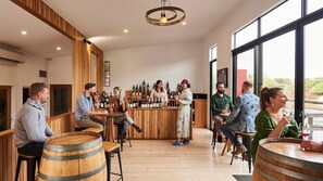 Angolo bar con arredi in legno, bancone e diverse bottiglie.