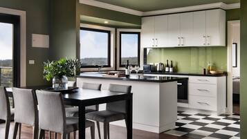 A modern kitchen with a dining area, large windows, and a view of the outdoors.