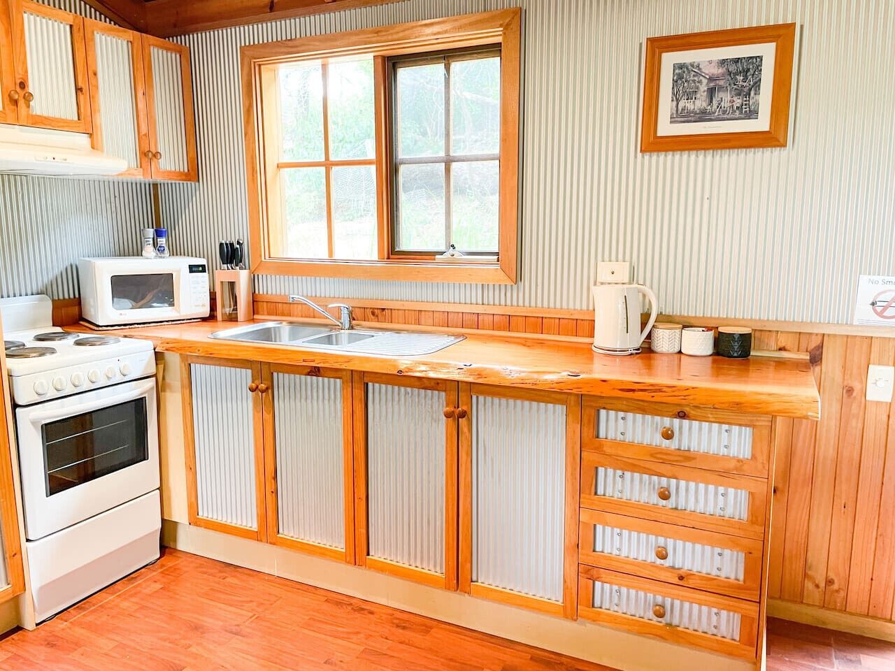 A kitchen with wooden cabinets, a stove, a microwave, and a window.