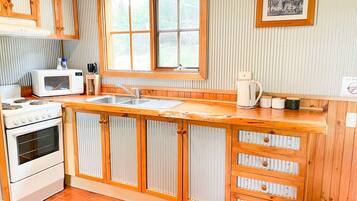 A kitchen with wooden cabinets, a stove, a microwave, and a window.
