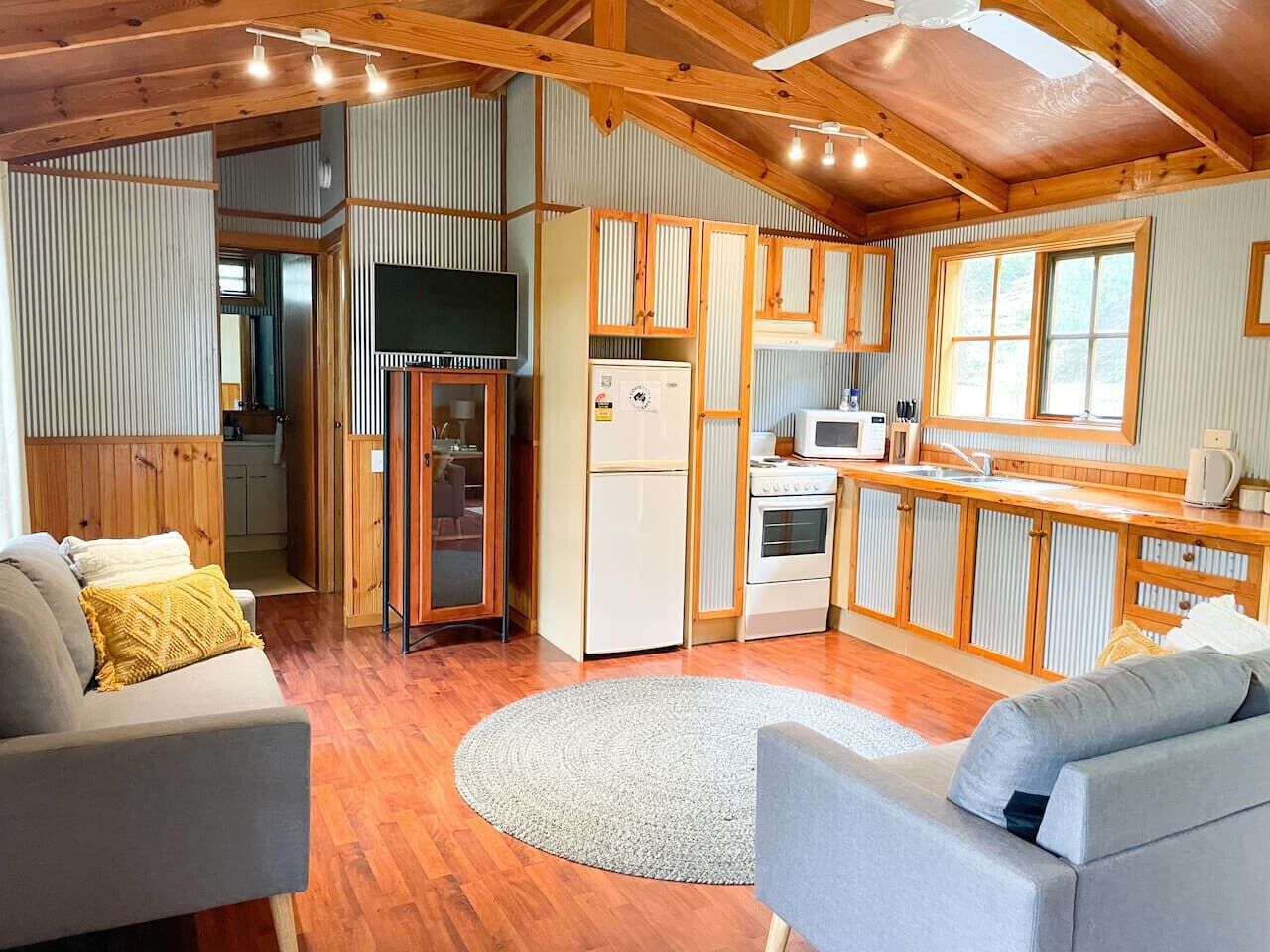 A cozy cabin interior with a living area, kitchen, and a dining space.