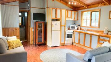 A cozy cabin interior with a living area, kitchen, and a dining space.