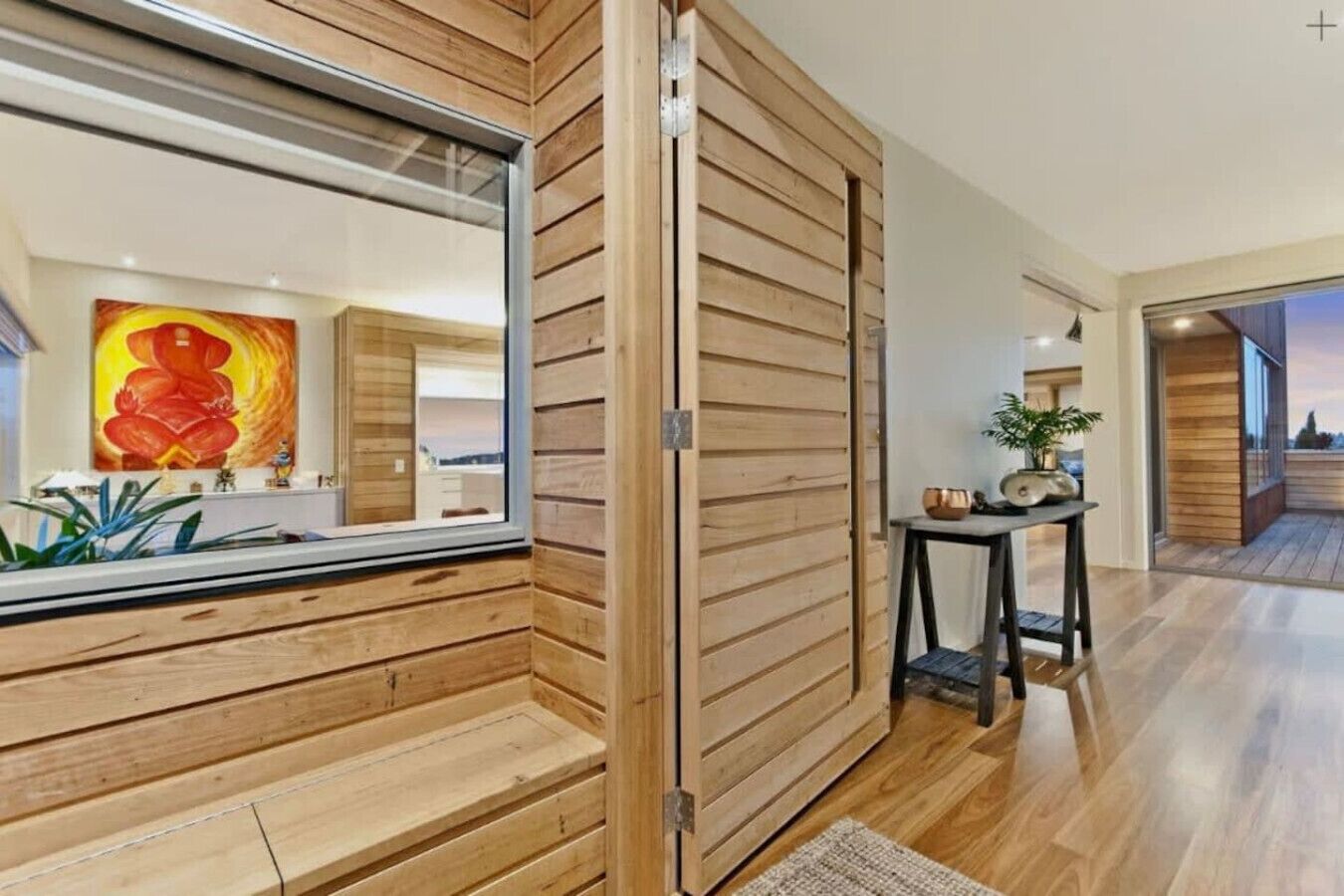 A modern interior with wooden paneling, a large mirror, and a view of a cityscape.
