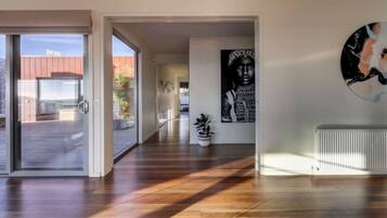 A modern interior with a wooden floor, a potted plant, and a wall-mounted artwork.