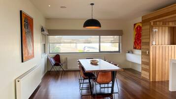 A dining area with a table and chairs, a radiator, and a window with a view of the outside.