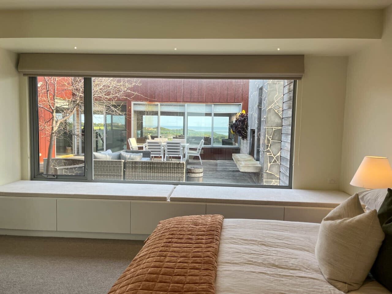 A bedroom with a large window seat overlooking a patio area with outdoor furniture.