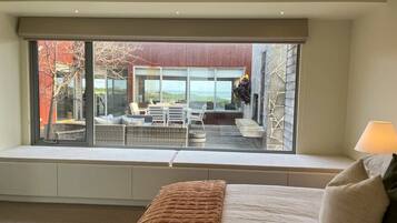A bedroom with a large window seat overlooking a patio area with outdoor furniture.