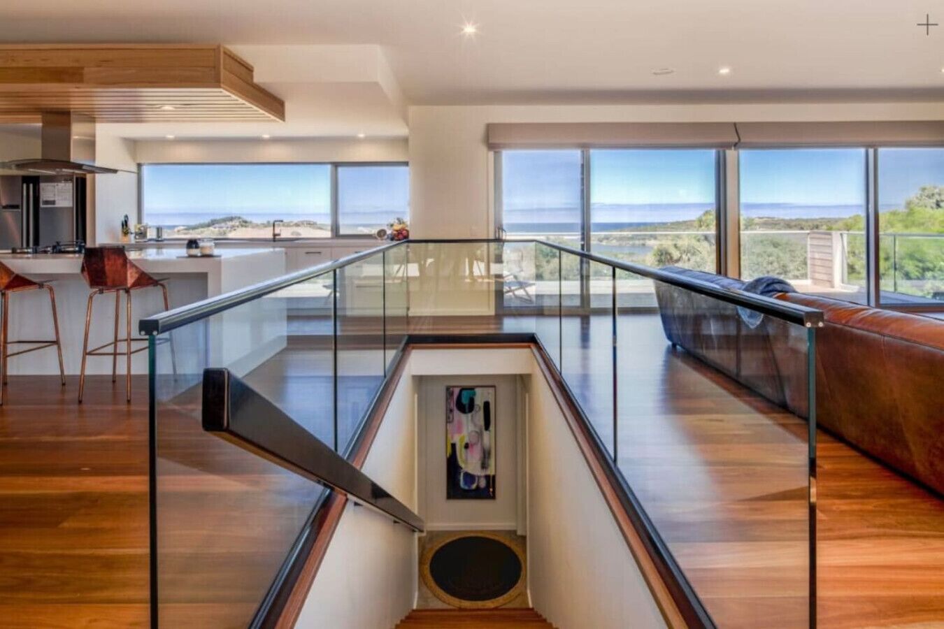 A spacious living area with a glass railing, a staircase, and a view of the outdoors.