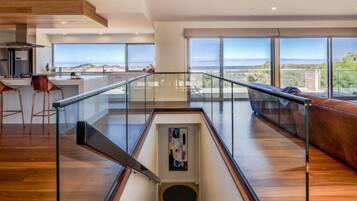 A spacious living area with a glass railing, a staircase, and a view of the outdoors.