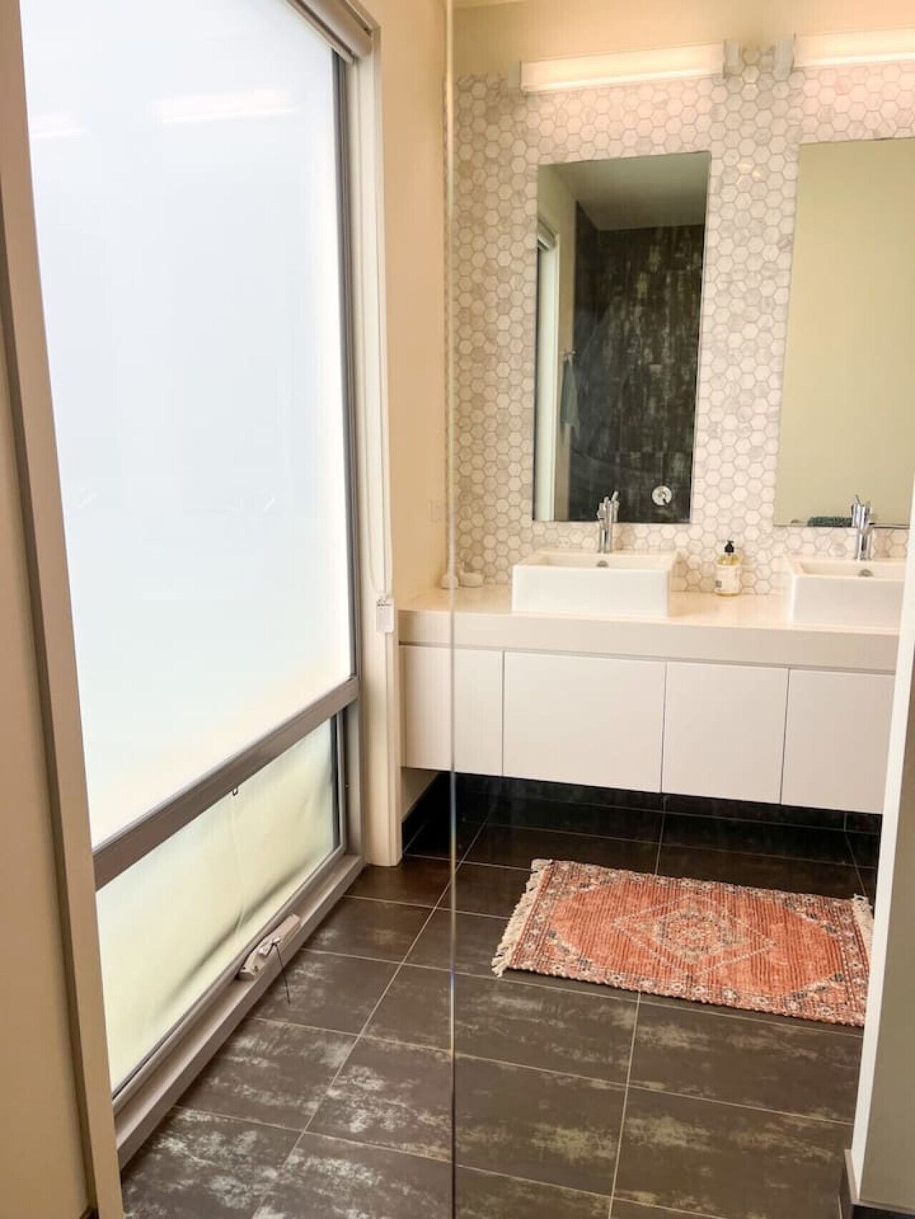 A bathroom with two sinks, a large mirror, and a patterned hexagonal wall design.