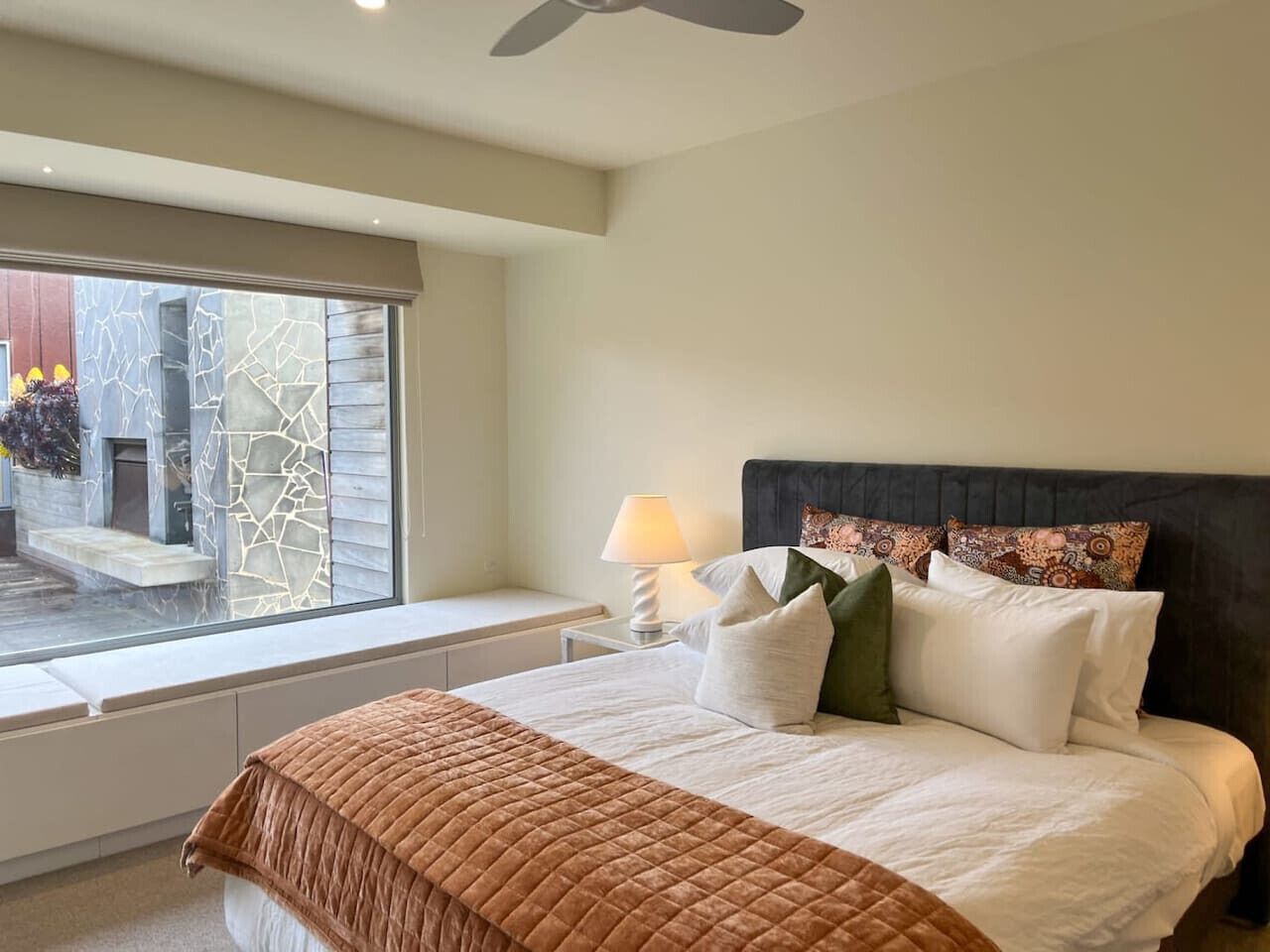 A bedroom with a bed, a window, a nightstand, and a ceiling fan.