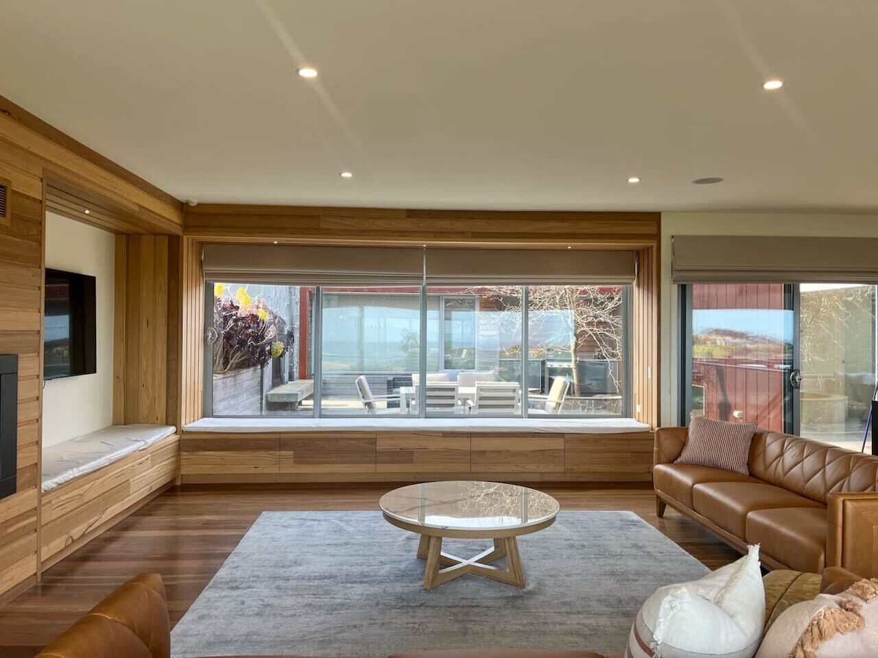 A modern living room with a large window, a round coffee table, and a leather sofa.