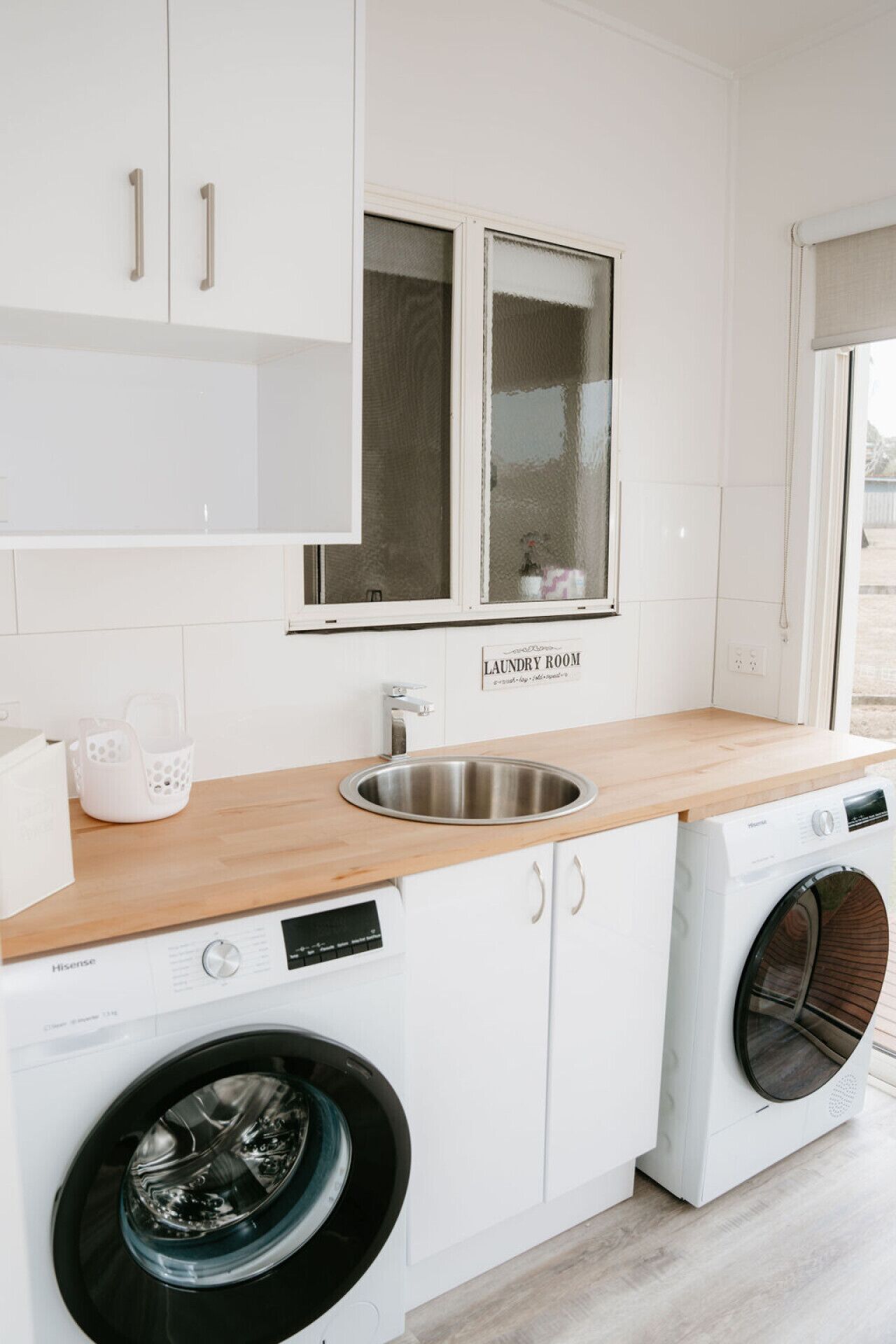 Une buanderie équipée d’un évier, d’un lave-linge et d’un sèche-linge.