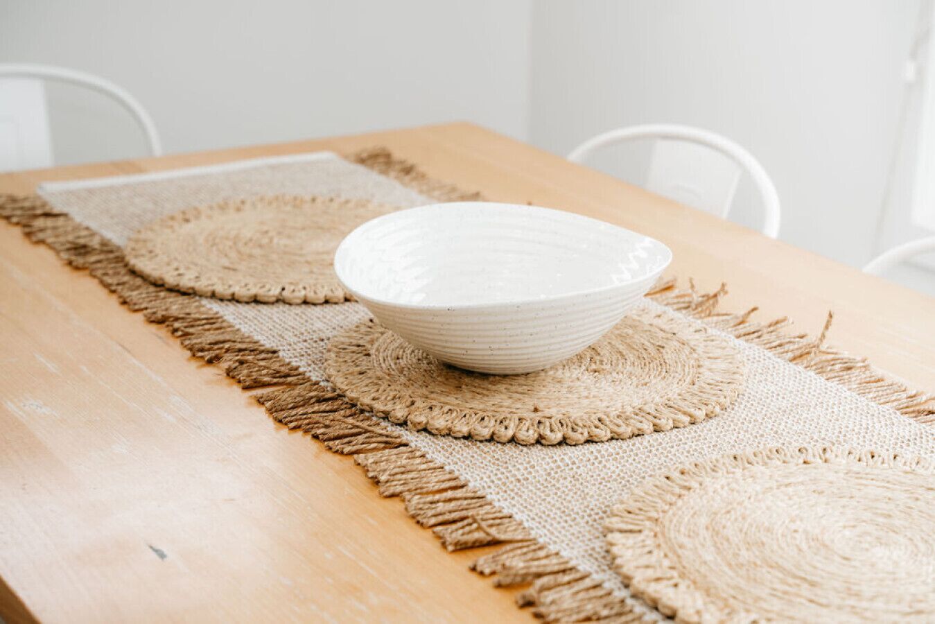 A wooden table with a woven placemat and a bowl placed on it.