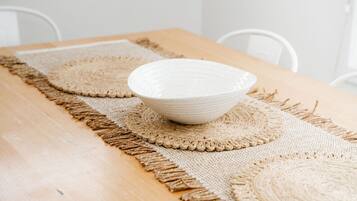 A wooden table with a woven placemat and a bowl placed on it.