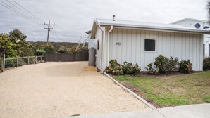 A single-story building with a gravel driveway leading to a gated entrance.