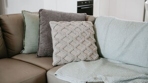 A beige sofa with three pillows in a living room.