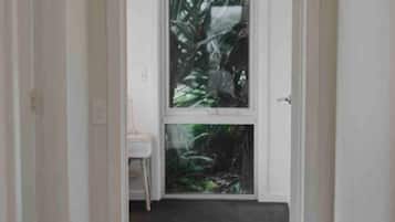 A narrow hallway with a door leading to a room with a large window.