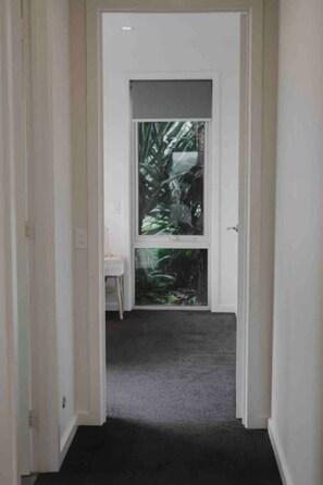 A narrow hallway with a door leading to a room with a large window.